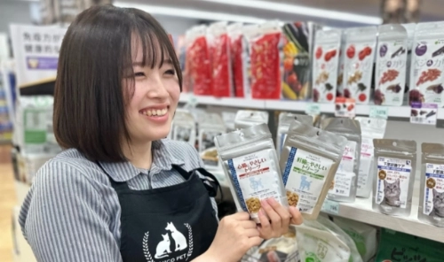 ペットショップの店員が、ペットフードを手にもってお客さまへご案内している様子