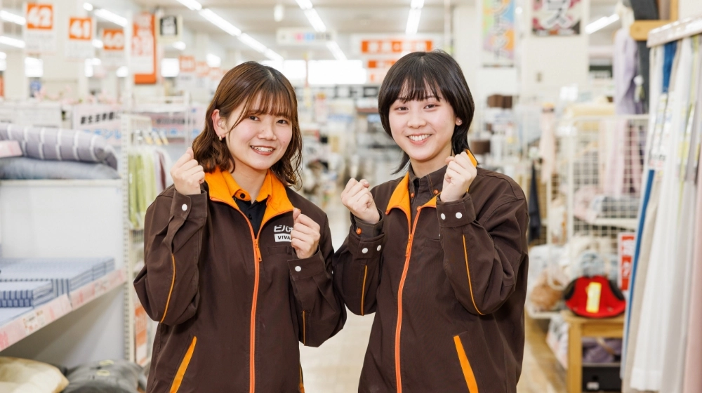 従業員2名が、笑顔で正面を向いてポーズをとっている様子