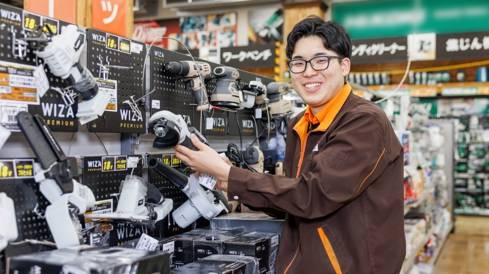 資材館の従業員が工具を手にもって笑顔で正面を向いている様子