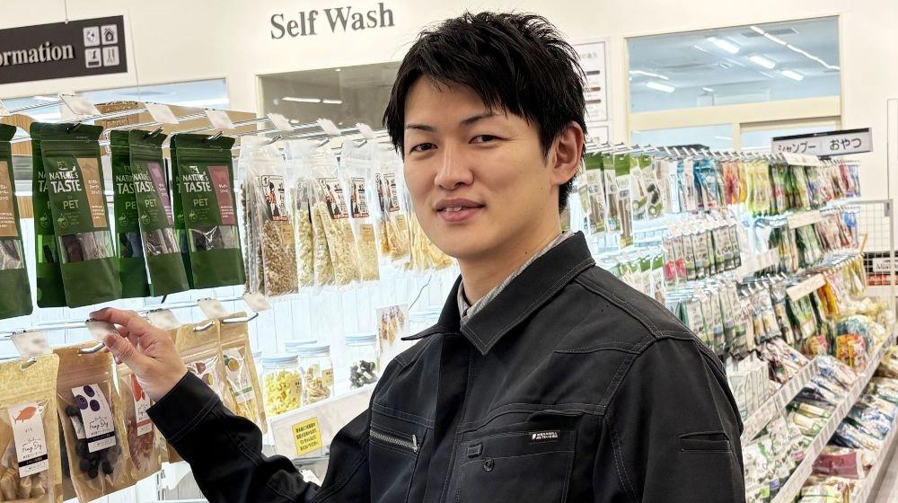 ペットショップの従業員が商品に手をかけて笑顔で正面を向いている様子